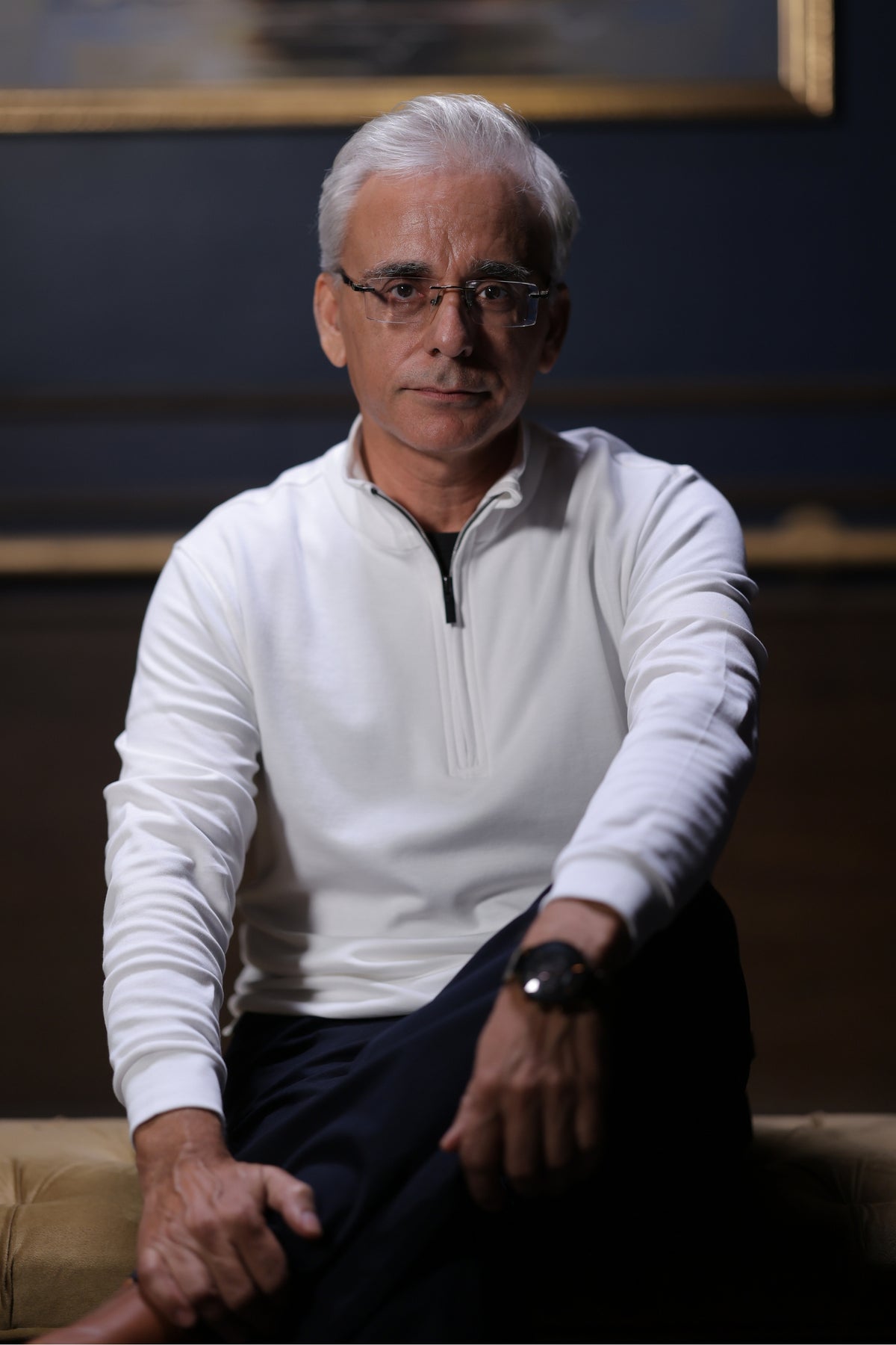 Man seated in a white quarter-zip top