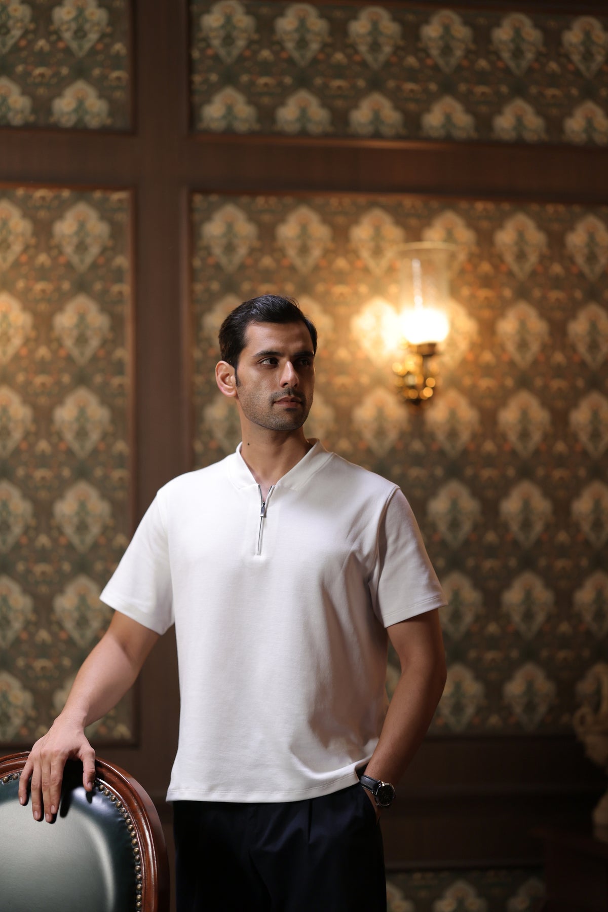 Man wearing a white polo in a patterned room