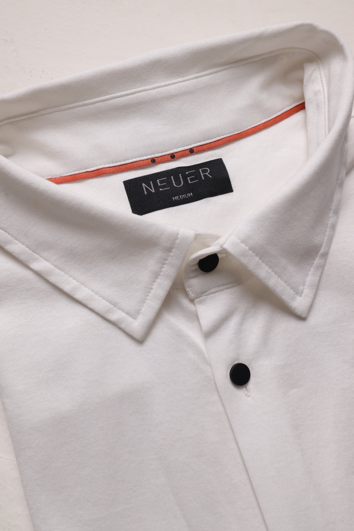 White NEUER collar and red trim detail
