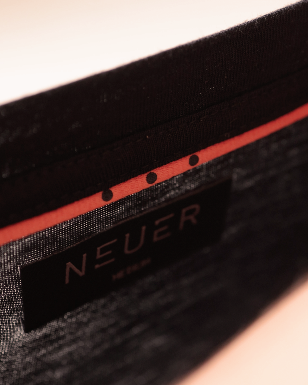 NEUER black fabric label and red trim