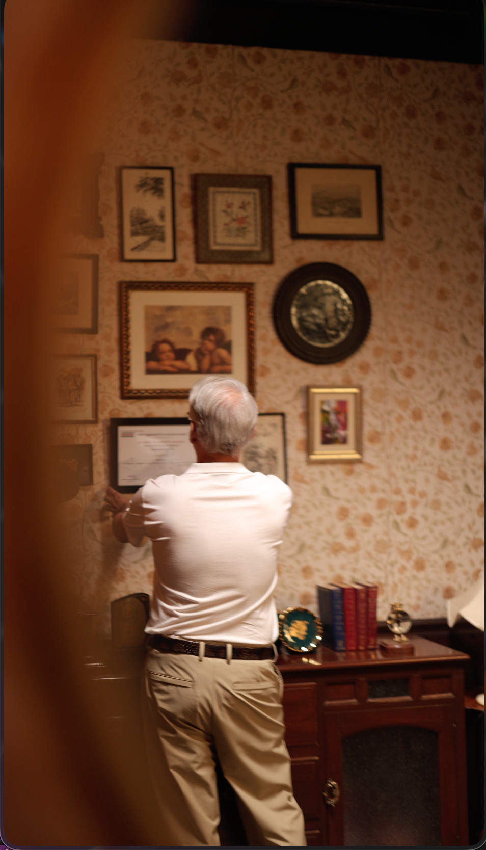 Man in ivory viewing framed photographs